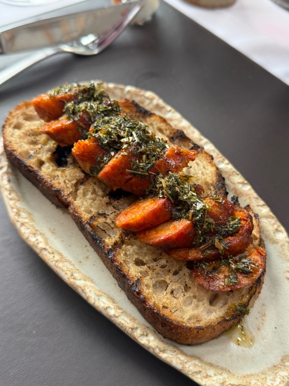 Choripán argentino com chorizo grelhado, chimichurri verde fresco sobre pão tostado