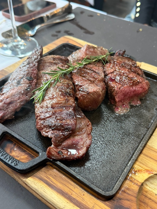 Corte Denver grelhado complementado com fatias generosas de entrecote, ramo de alecrim sobre tábua de ardósia preta