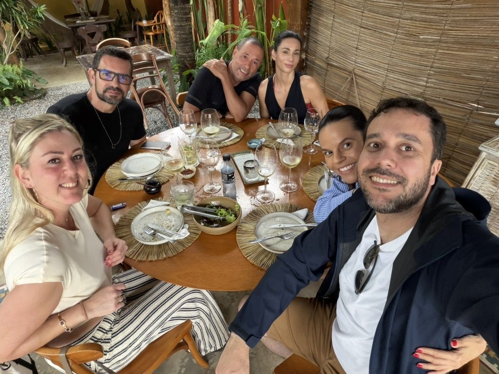 Mesa cheia de amigos, com vinho e comida, durante a estadia no Pedras do Patacho